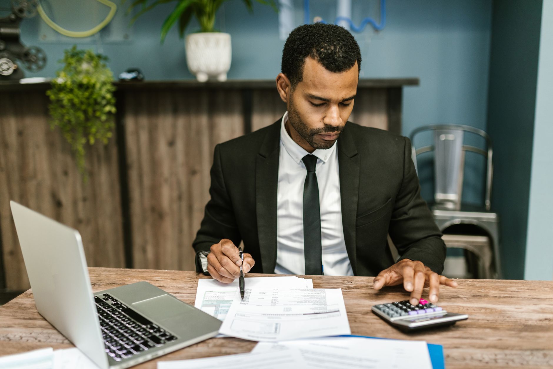 An accountant reviewing financials with a calculator and laptop