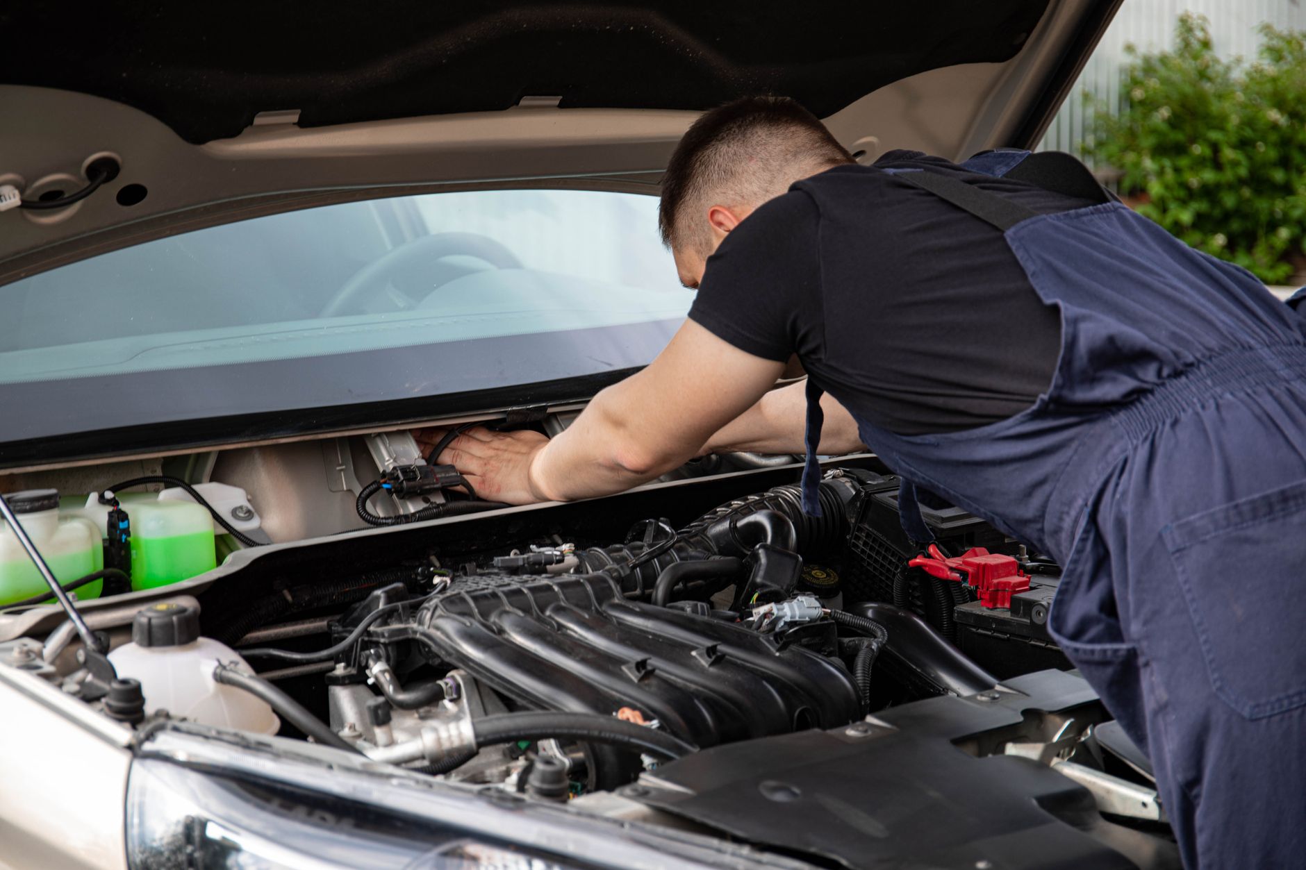 A mechanic working under the hood on an engine