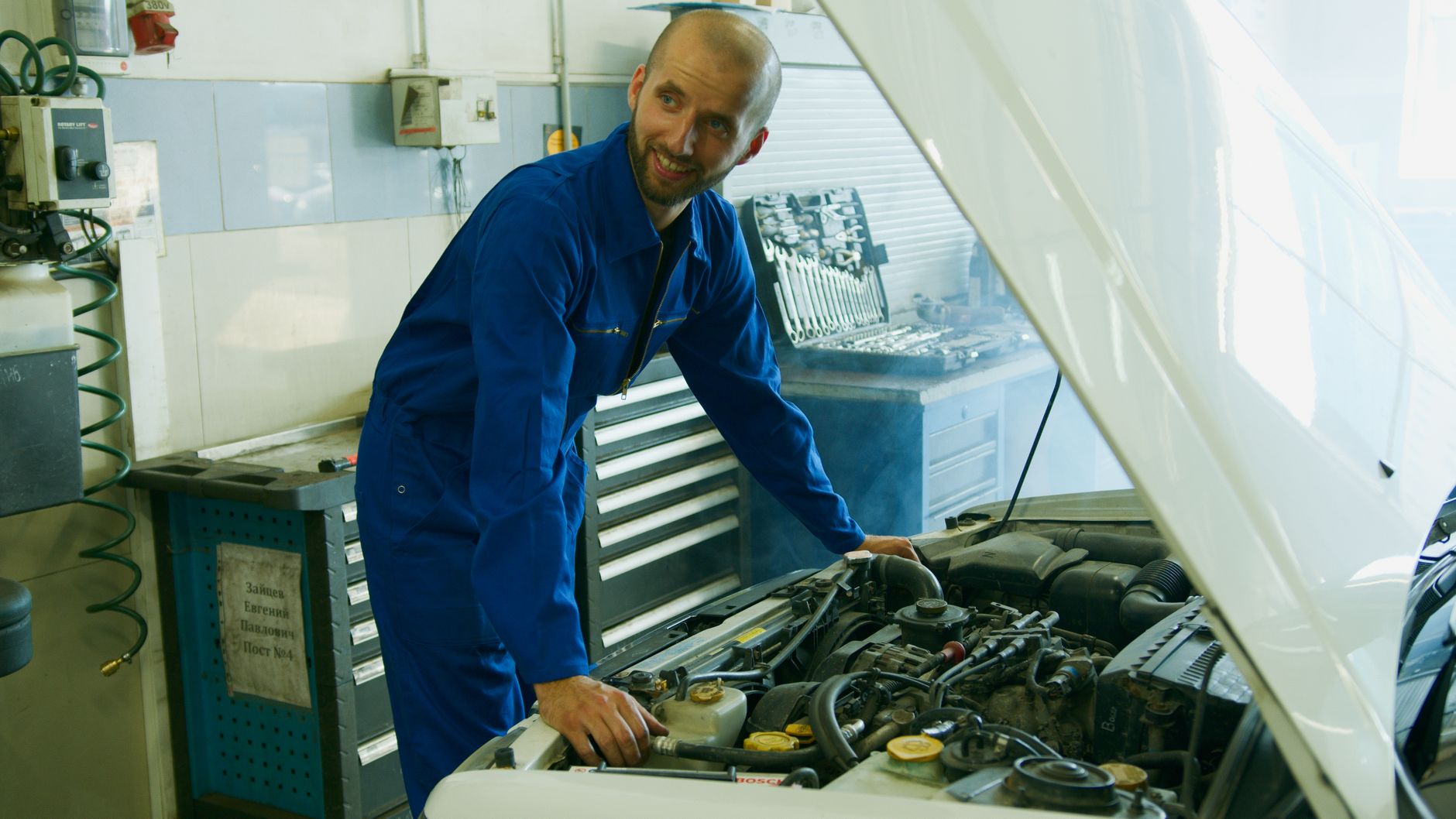 A smiling mechanic checking over a customer's engine
