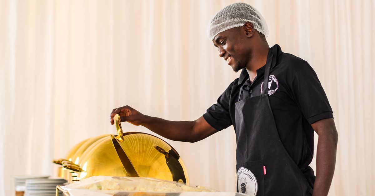 A caterer arranging a plated dish at an event buffet table