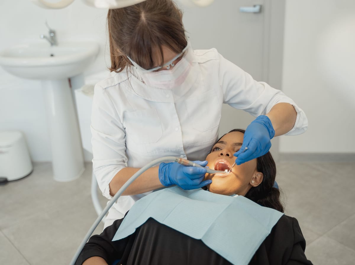 A dentist in a mask and gloves treating a patient in the chair, focused on the work