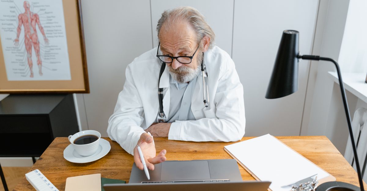 A dermatologist reviewing charts on a laptop between patient appointments