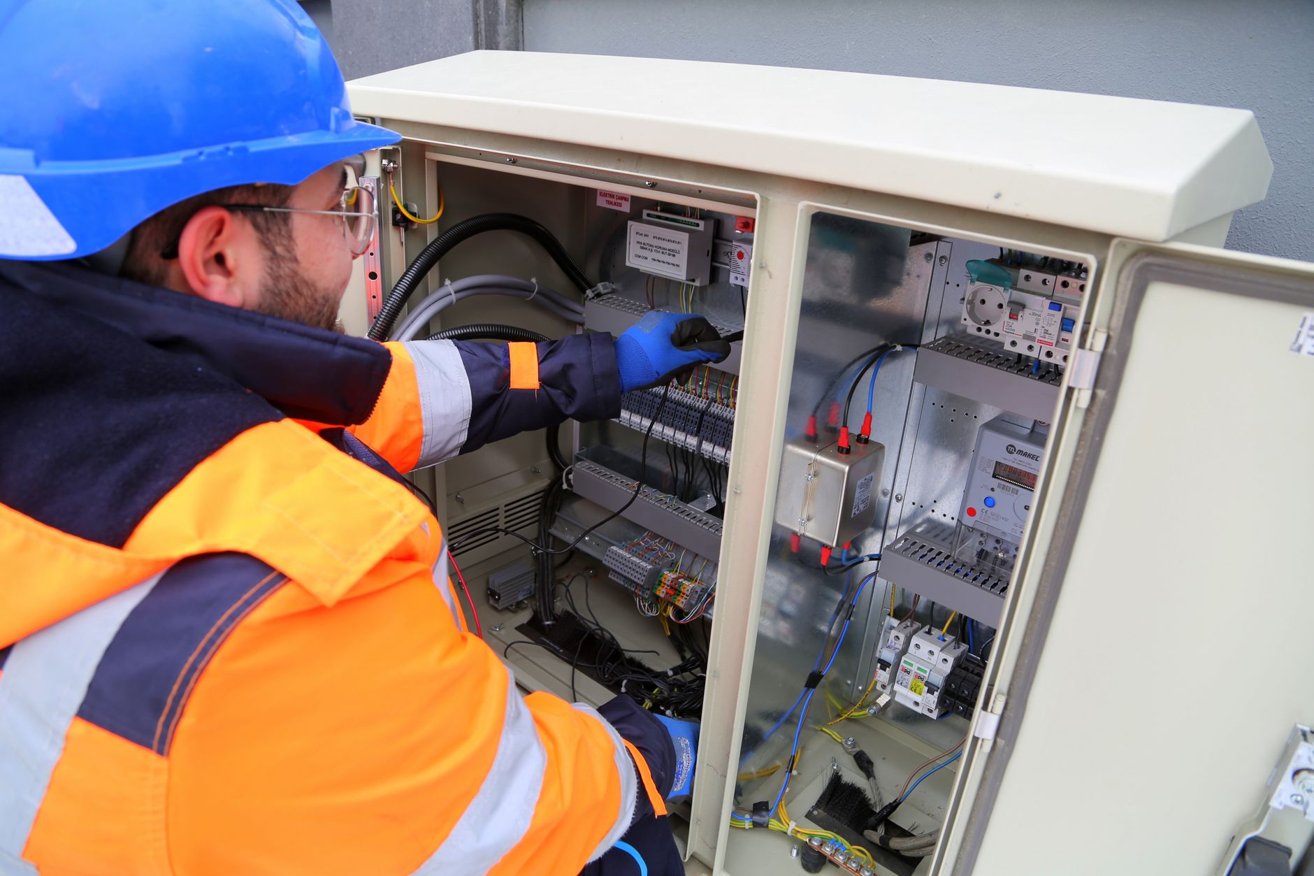 A licensed electrician working on an outdoor electrical panel