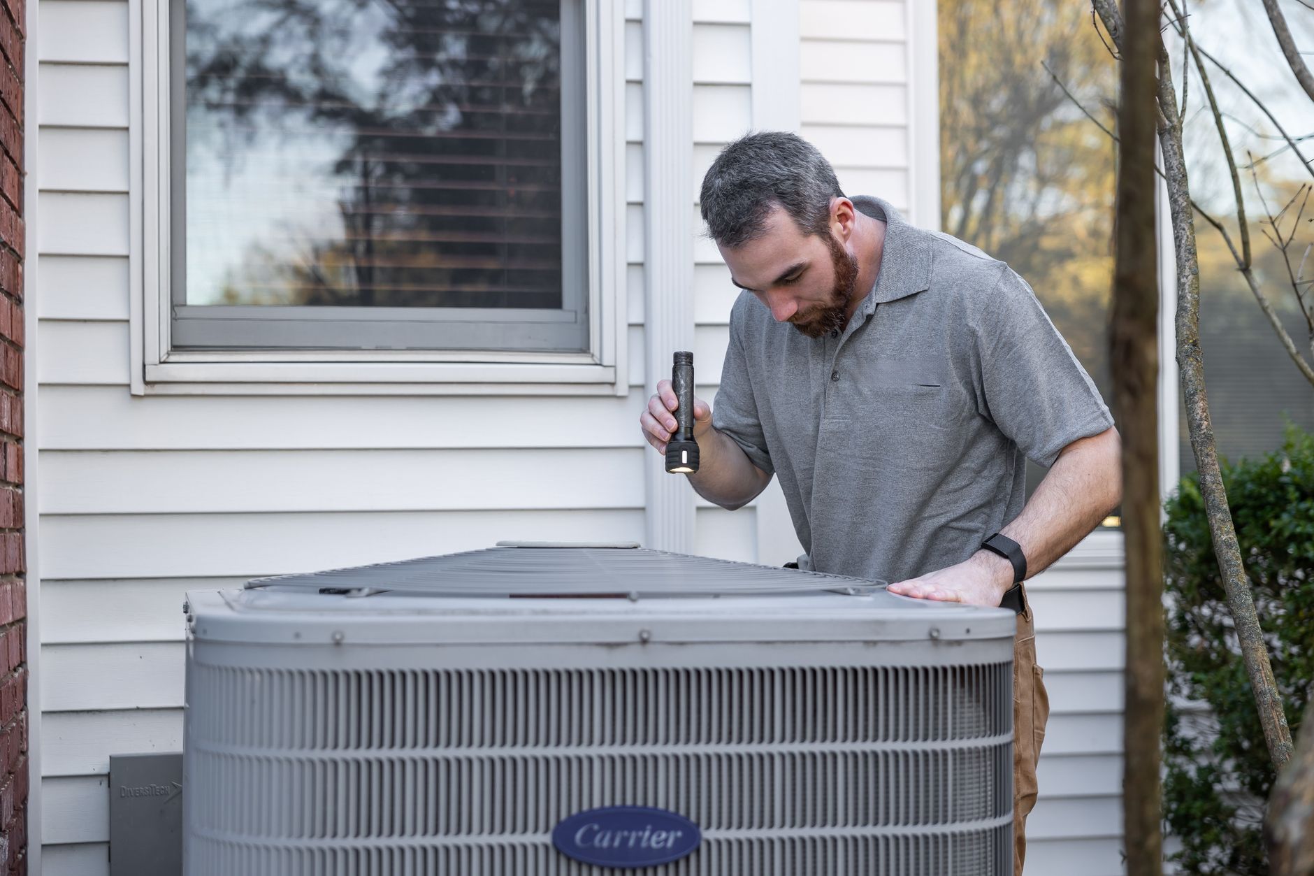 An HVAC technician inspecting an outdoor air conditioning unit