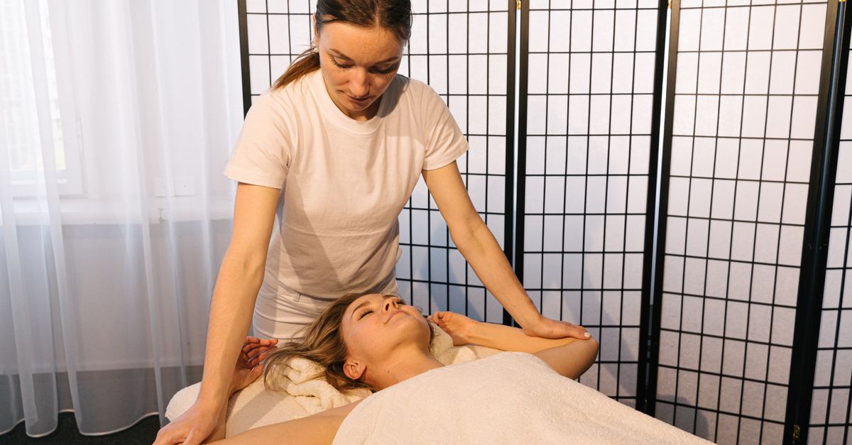 A massage therapist giving a client a relaxing deep tissue massage in a calm, softly lit studio