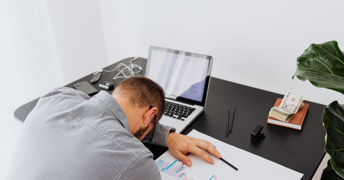 A loan officer on the phone reviewing numbers at a desk stacked with files