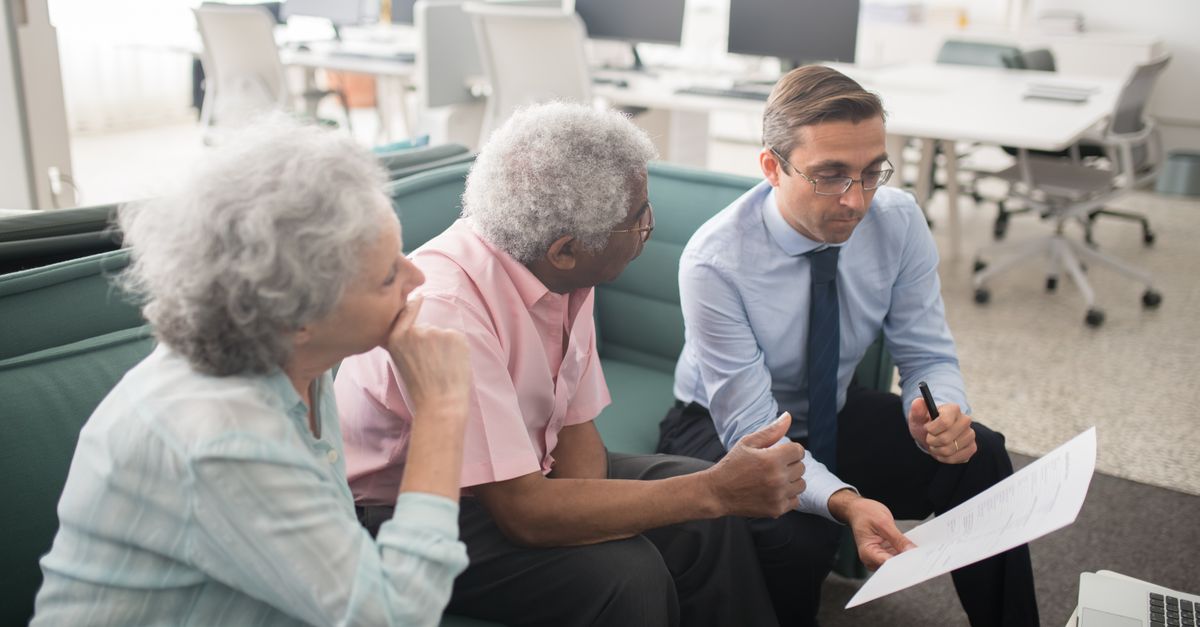 A mortgage broker reviewing loan paperwork with a couple in a bright office