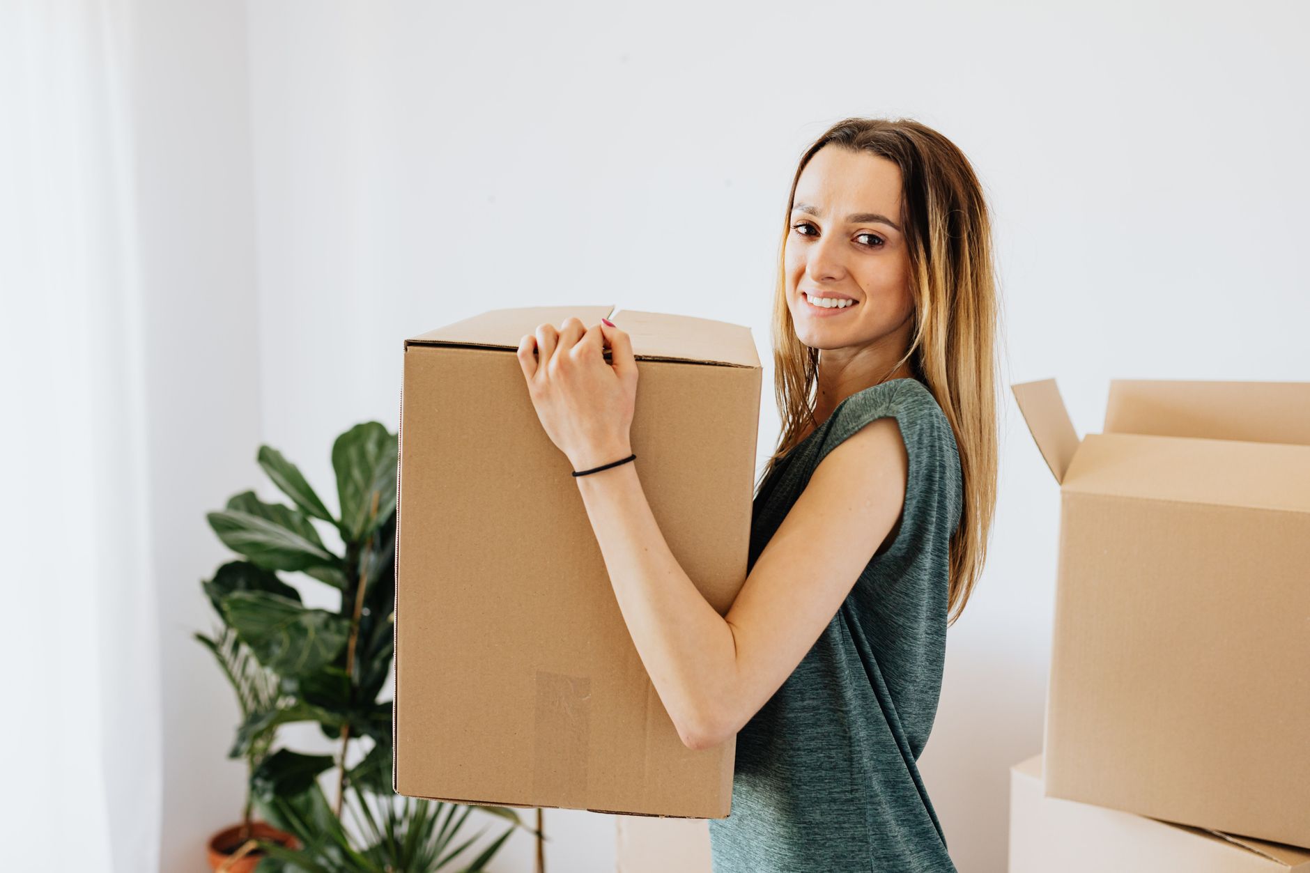 A person carrying a cardboard moving box while preparing to move