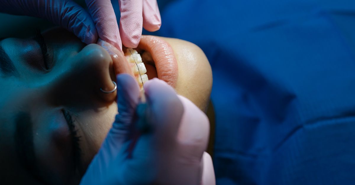 An orthodontist checking a teenage patient's braces in a bright modern practice