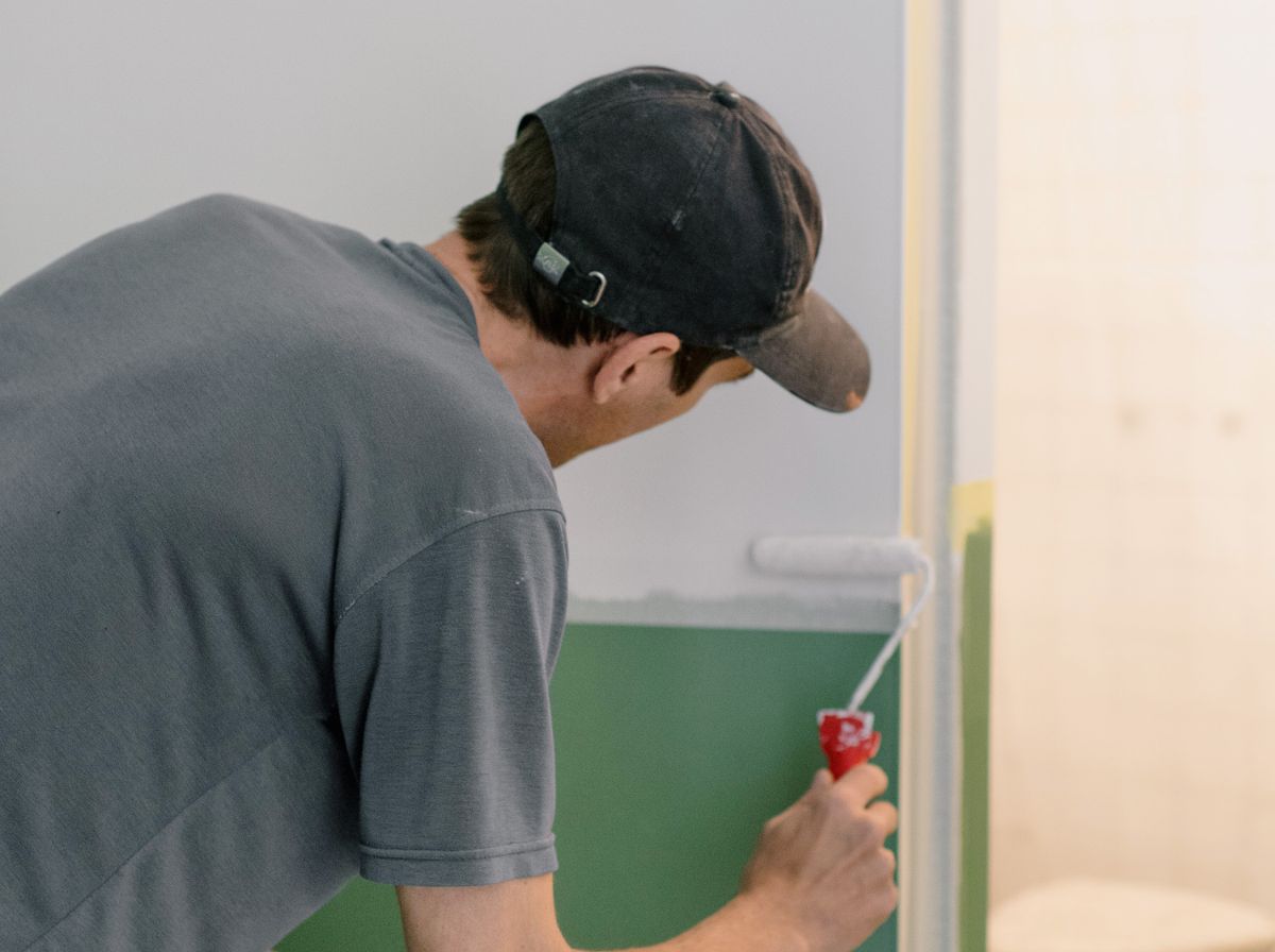 A painter focused on carefully rolling paint onto a wall, heads down on the job