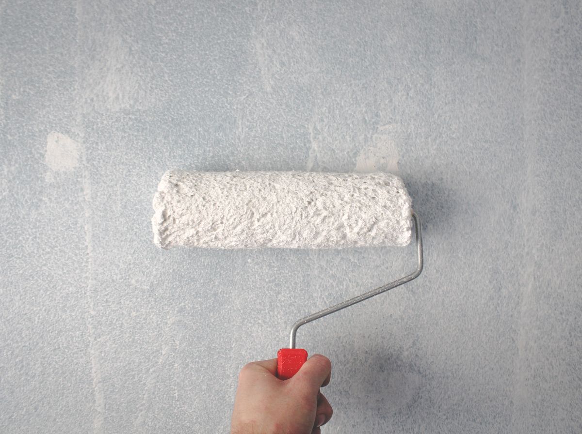 A paint roller applying a smooth, fresh coat of white paint to a wall