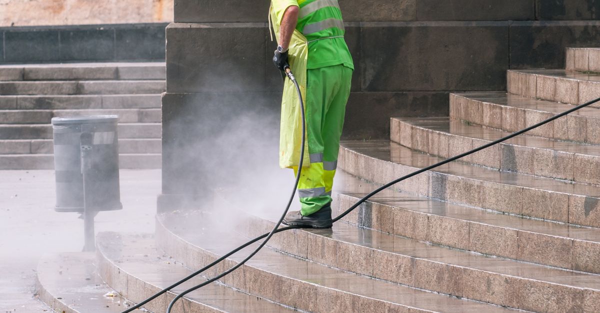 A pressure washing technician blasting years of grime off a concrete driveway