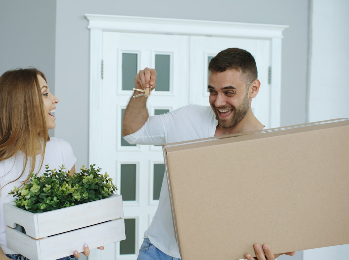 A happy couple holding moving boxes and house keys in their new home