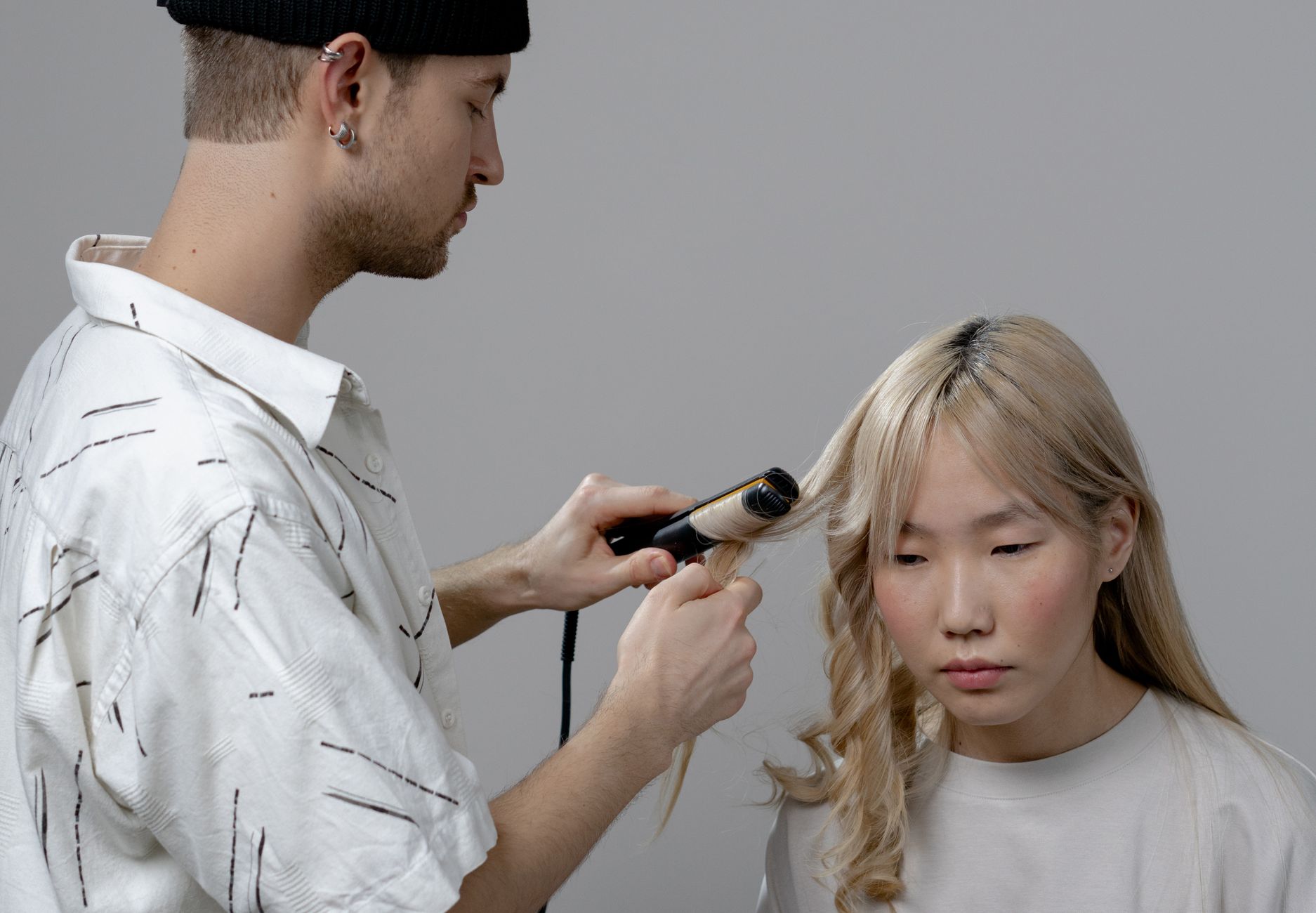 A hairstylist styling a client's hair with a curling iron