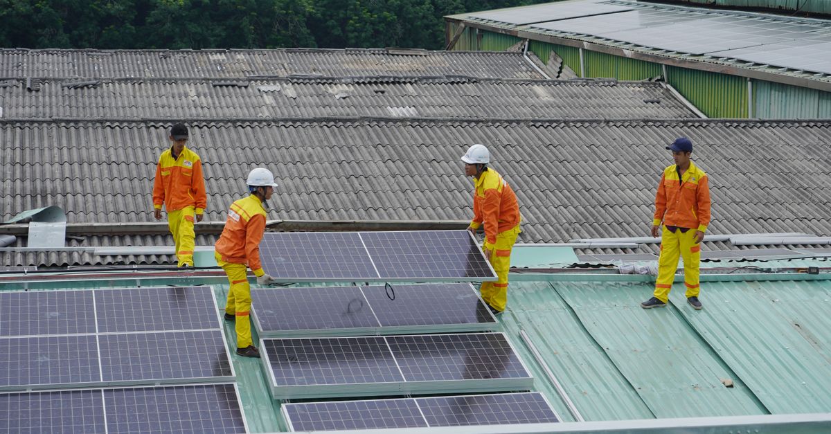 A solar installation crew mounting panels on a residential roof in bright daylight